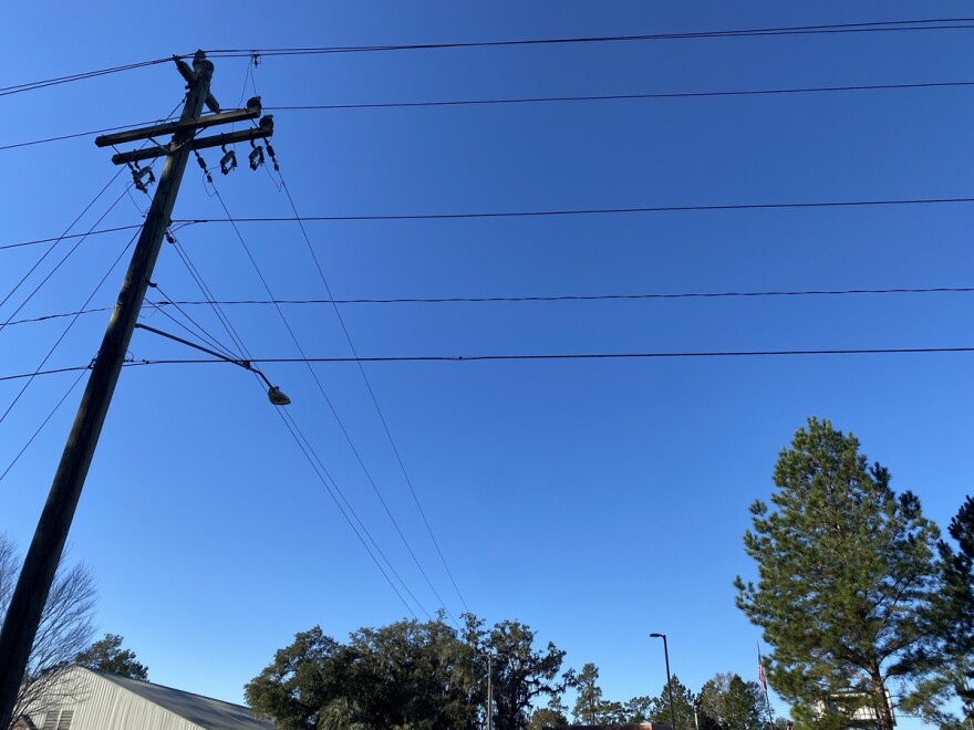 A power pole and power lines with trees below