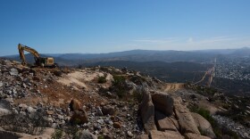 Construction crews work on a new border wall segment on Kuuchamaa Mountain, Friday, April 24, 2026, seen from Tecate, Mexico. (AP Photo/Gregory Bull)