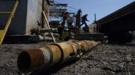 An oil well worker moves equipment at a site on the Rooke family ranch where an orphaned well was plugged. (Eric Gay/AP)