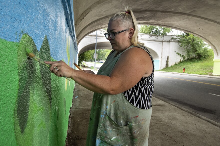 With a steady hand, artist Julie Farstad paints the heart-shaped leaf of a redbud tree in different shades of green. This summer she’s working on a series of murals featuring Missouri’s native plants and insects as part of her ongoing project “Flowers for Marlborough.”