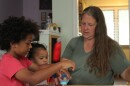 Liz Arnold plays with two children at Just Like Mine Daycare in Lincoln, Nebraska, on DATE. She’s certified to care for up to 10 children in her home, but this summer she is taking care of six.