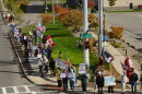 Ralliers stand at the street corner of Hiawatha Blvd. and Solar Street in Syracuse holding signs urging passersby to vote early.