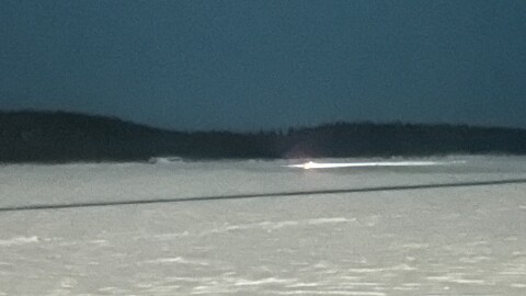 The headlight of race judge Steven Hilton's borrowed snow machine seen from the banks of the Yukon River on Feb. 14, 2026. Hilton was stuck for about an hour. (Shelby Herbert/KUAC)