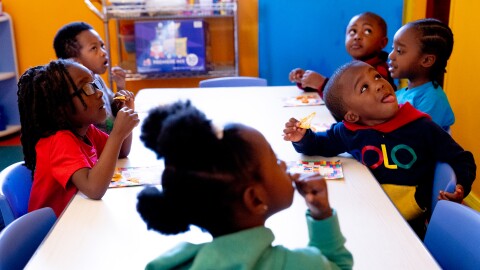 Legend, 4, left, and Paison, 3, right, look up at an education video while eating a snack on Monday, April 10, 2023, at the childcare center in Penrose.