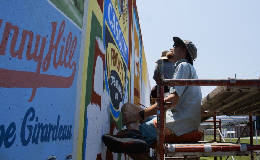 Painter Jess Wells glances at the meticulous work the group is doing along the new Cape Girardeau, Mo., flood wall mural on August 11th.