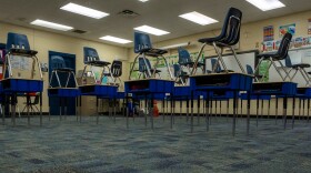 Blue chairs stacked on top of desks in a classroom