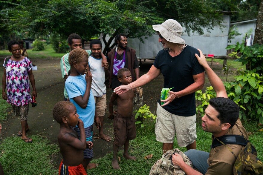 Jon O'Neill, a writer from Florida, hands out candy to children as he and Justin Taylan look for World War II wreckage. O'Neill's father was an American pilot who served in Papua New Guinea during World War II.