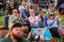 A group of seated audience members clapping at a music festival. 