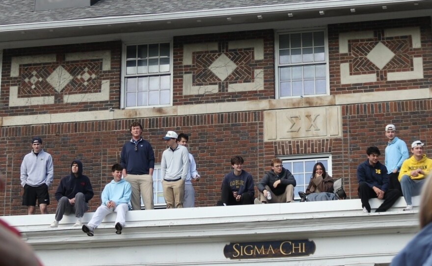 Students at Sigma Chi fraternity watch the parade from the roof.
