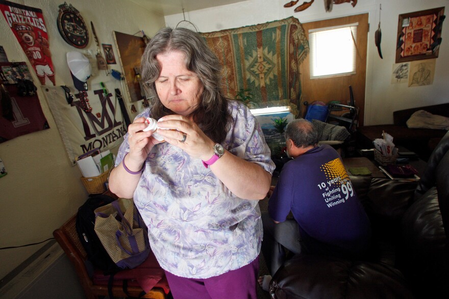 Celeste Thompson, 57, a home care worker in Missoula, Mont., examines a pill bottle in her home. Thompson cares for her husband, and worries that if she loses her Medicaid coverage she won't be able to afford to see a doctor.