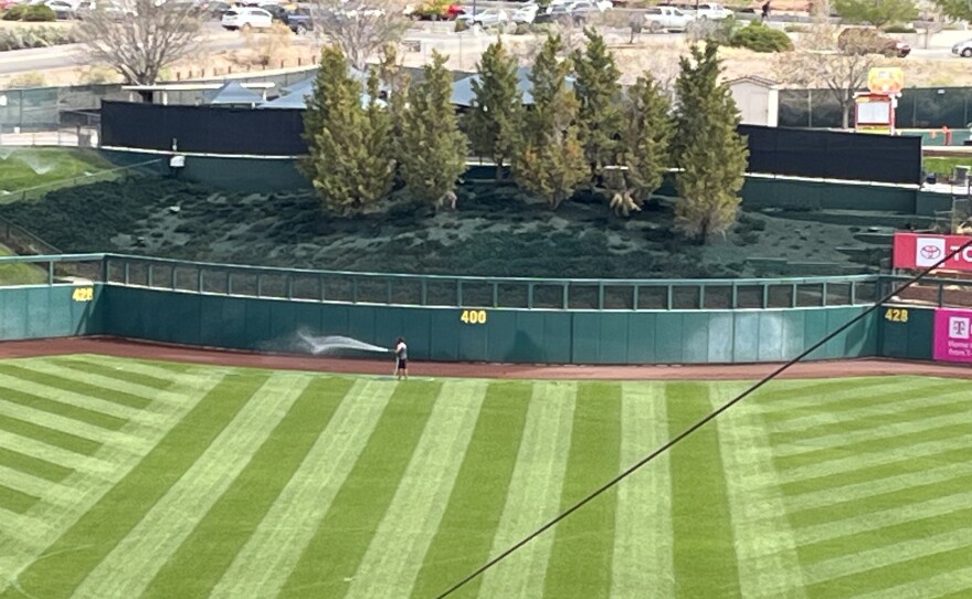 A grounds worker hoses down the warning track at Rio Grande Credit Union Field on March 30.