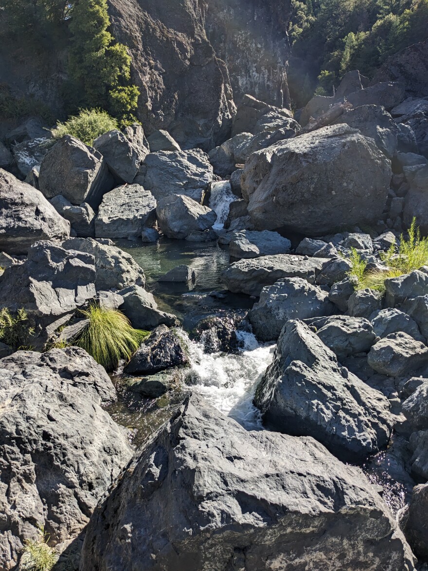 Large rocks surround a pool of water.
