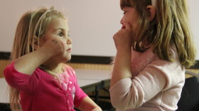 Two girls practice as they learn sign language. (Photo credit: Wikimedia Commons)