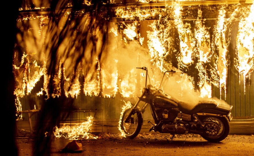 A structure and a motorcycle burn at an RV park during the Woolsey Fire in Malibu.