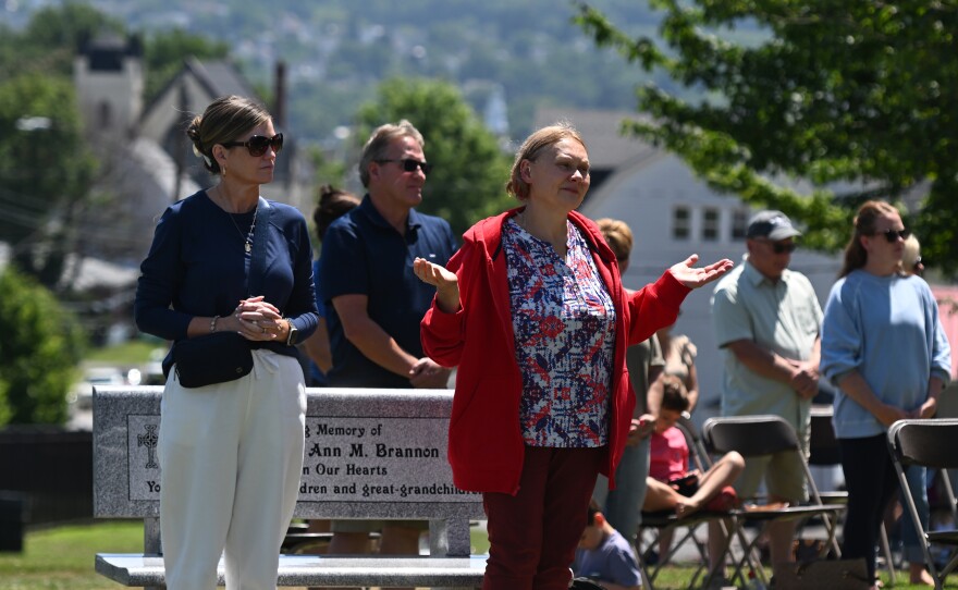 Parishioners stand in prayer during Mass on Monday.