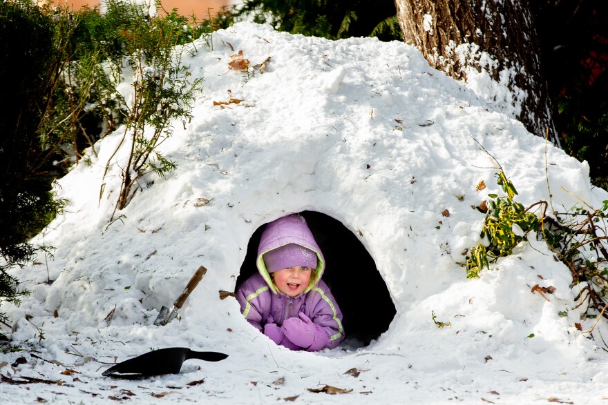 Agnes, 4, whose parents asked to not use their last name, lays in an igloo built by her siblings on Friday, Dec. 23, 2022, outside of her home in Benton Park.