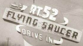 A black and white photograph of a roadside sign reading Rt. 52 Flying Saucer Drive In.