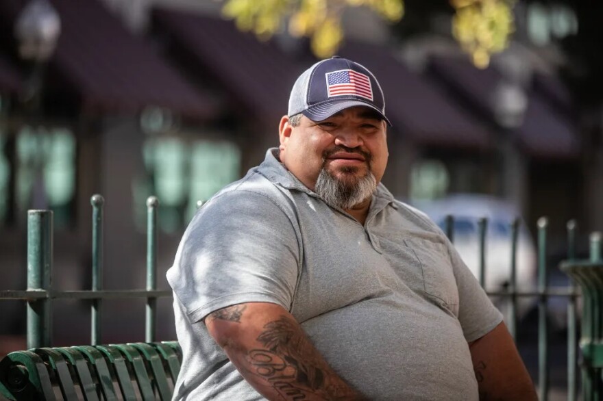 Aaron Barajas, an insurance agent, sits at a bench in front of his downtown Merced office on Nov. 7, 2024.