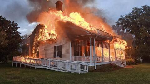 flames come out of the roof of a burning building