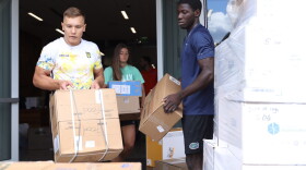Volunteers work to move boxes of donations into position for shipment. (Elliot Tritto/WUFT News)