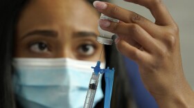 Licensed practical nurse Yokasta Castro, of Warwick, R.I., draws a Moderna COVID-19 vaccine into a syringe at a mass vaccination clinic, Wednesday, May 19, 2021, at Gillette Stadium, in Foxborough, Mass. A month after every adult in the U.S. became eligible for the vaccine, a distinct geographic pattern has emerged: The highest vaccination rates are concentrated in the Northeast, while the lowest ones are mostly in the South.