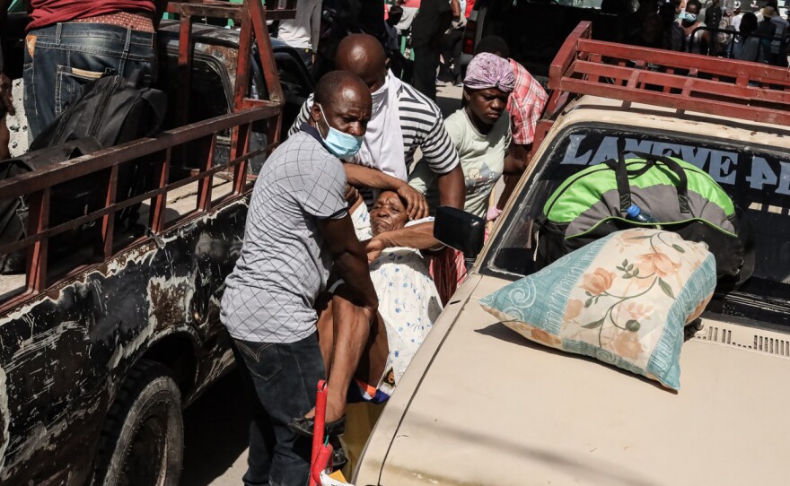 Residents carry an injured person through the streets in Les Cayes, Haiti, on Aug. 16.