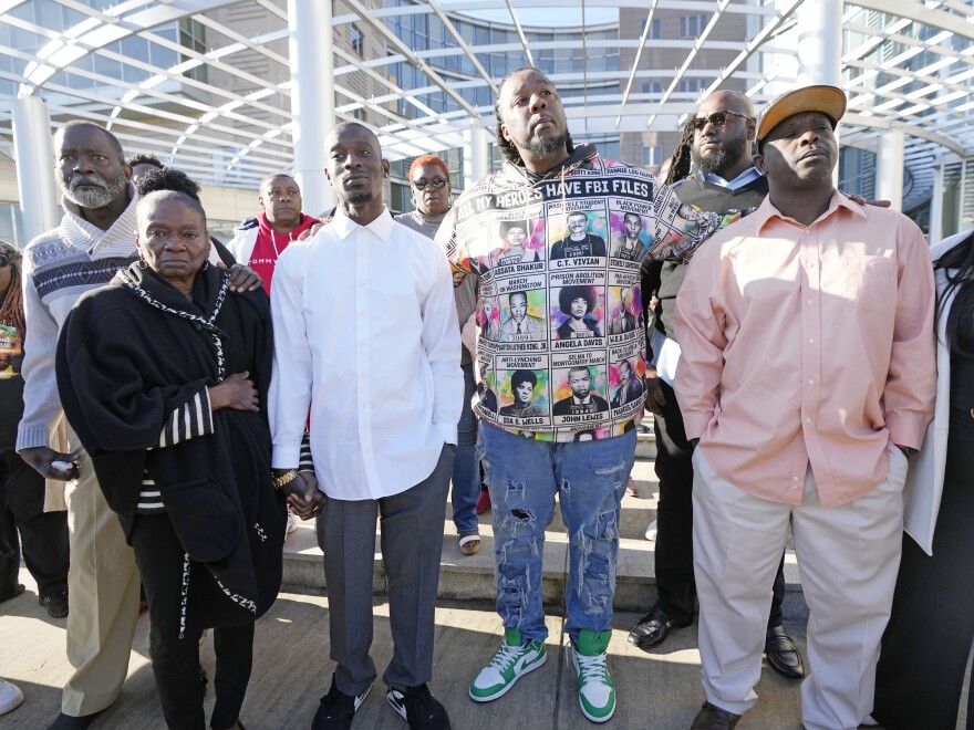 Michael Corey Jenkins, third from left, and Eddie Terrell Parker, right, stand with supporters outside the courthouse in Jackson, Miss., Tuesday, March 19, 2024, calling for harsh penalties against six former law enforcement officers who committed numerous acts of racially motivated, violent torture on himself and his friend Eddie Terrell Parker in 2023.