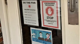 Signs on the door of Village Deli in downtown Bloomington advising customers about COVID-19.