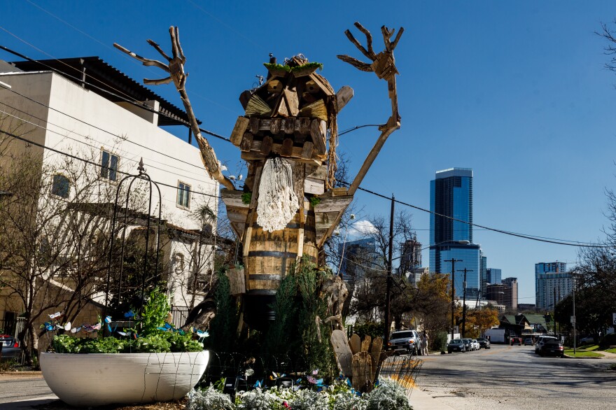 A large wooden statue of a troll sits in the middle of the road with its arms raised wildly.