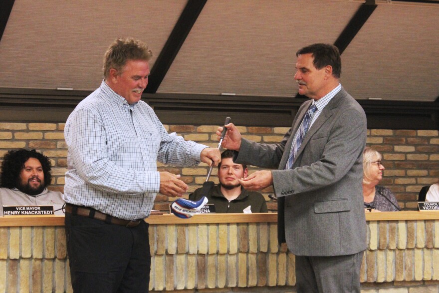 Outgoing Kenai Mayor Brian Gabriel (left) accepts a golf club from incoming Mayor Henry Knackstedt (right) after his last city council meeting on Wednesday, Oct. 15, 2025 in Kenai, Alaska.