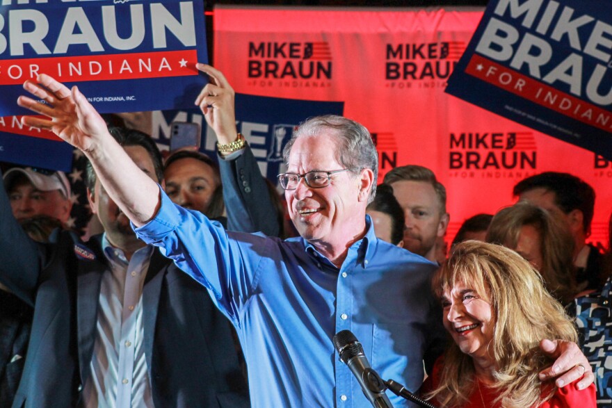 Mike Braun, with one arm wrapped around his wife Maureen, waves to a crowd of supporters at his primary election night celebration on May 7, 2024.
