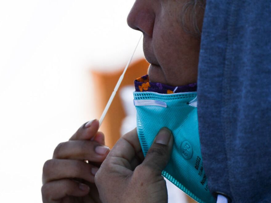 A person swabs their nose as they receive testing for both rapid antigen and PCR COVID-19 tests at a Reliant Health Services testing site in Hawthorne, Calif., on Jan. 18, 2022.