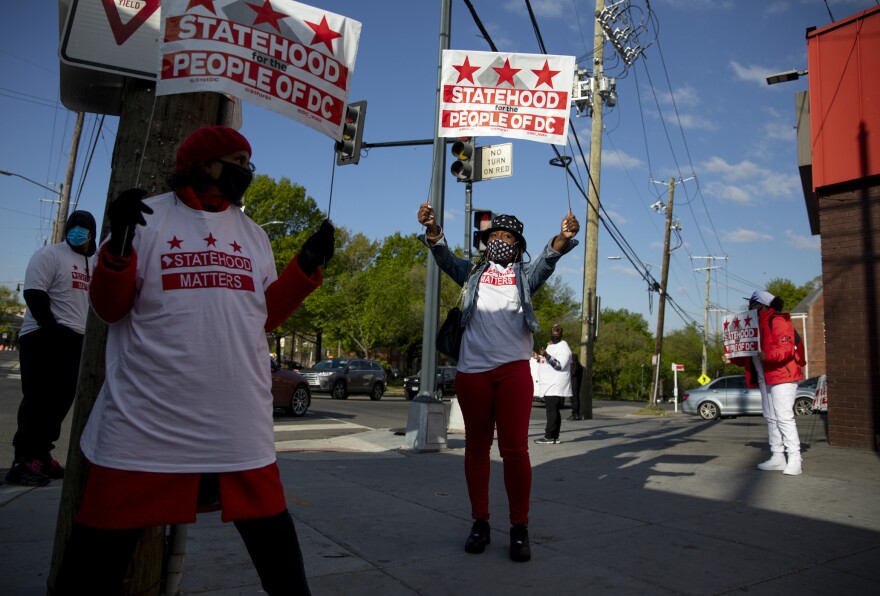 Supporters stand at the corner of Martin Luther King Jr. Ave & Malcolm X Ave SE in Ward 8 in Washington, D.C.