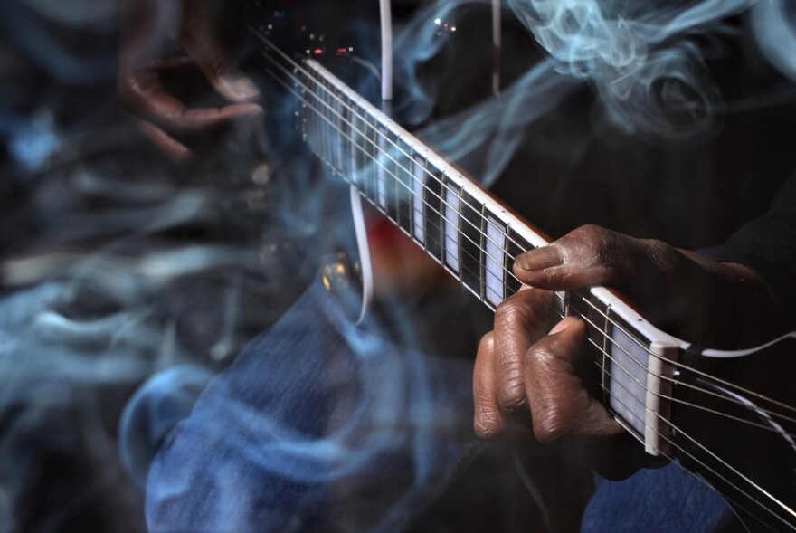 Black guitarist close-up on fingers, playing in smoke