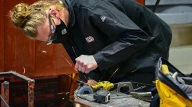A career and technical education high school student in Elkhart grinds a piece of metal before welding it.