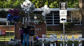 A family pays their respects next to crosses bearing the names of Tuesday's shooting victims at Robb Elementary School in Uvalde, Texas, Thursday, May 26, 2022. (Jae C. Hong/AP)