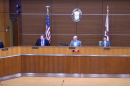 Meeting in the county commission room, four of the five county commissioners, with the American flag and Florida flag behind them