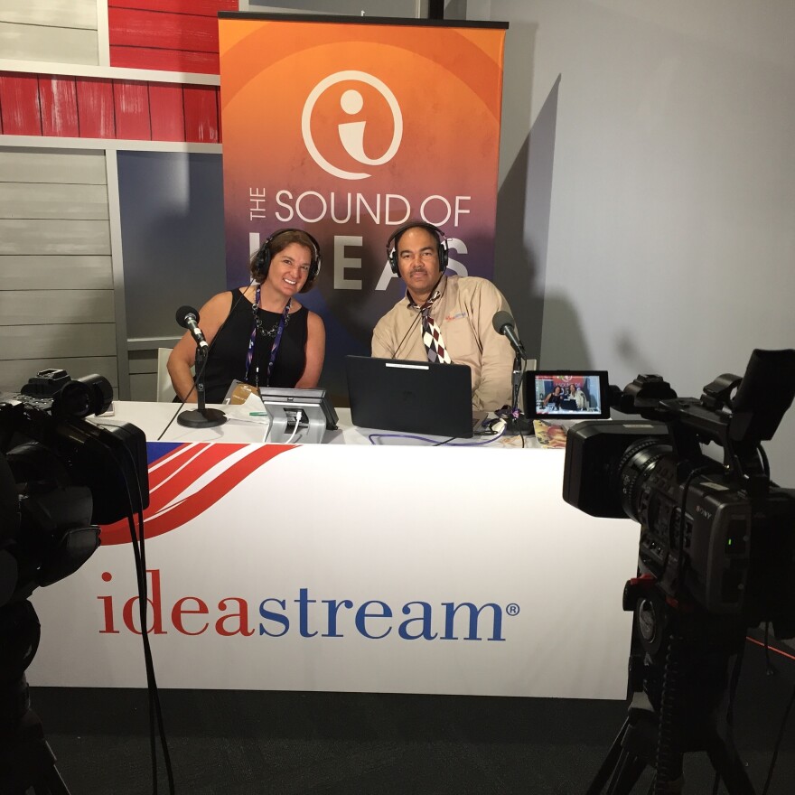  "Sound of Ideas" managing producer Amy Cummings with host Rick Jackson sit behind a table with TV cameras pointed at them during the Republican National Convention in Cleveland in 2016.