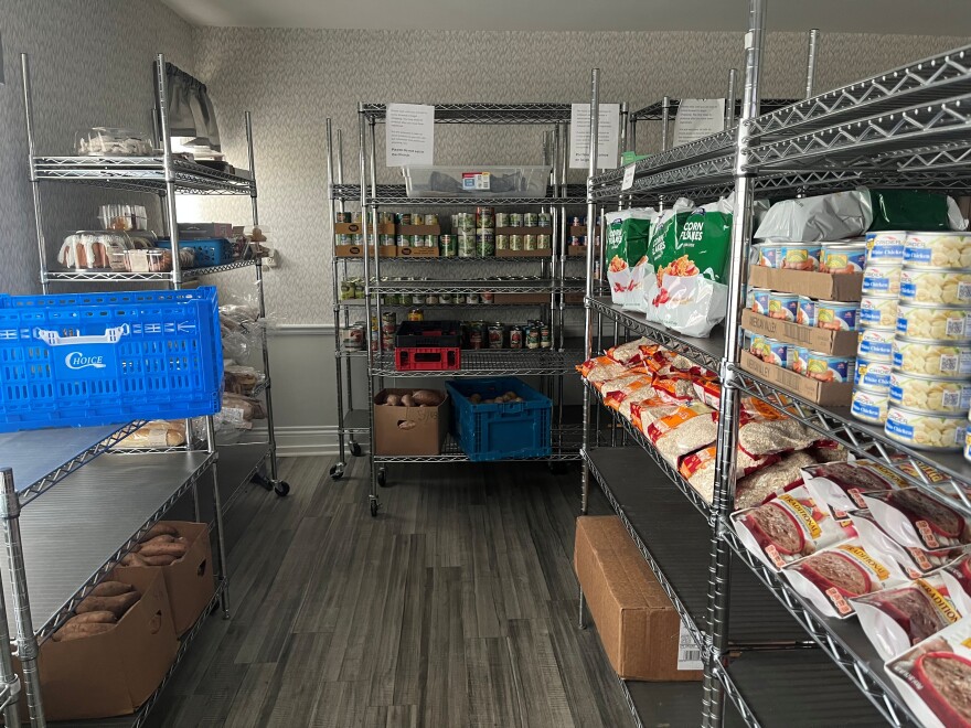 Canned food, potatoes, and other shelf stable groceries on metal shelves and in boxes.