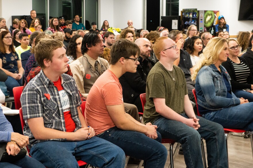 A seated audience listens intently to a presenter.