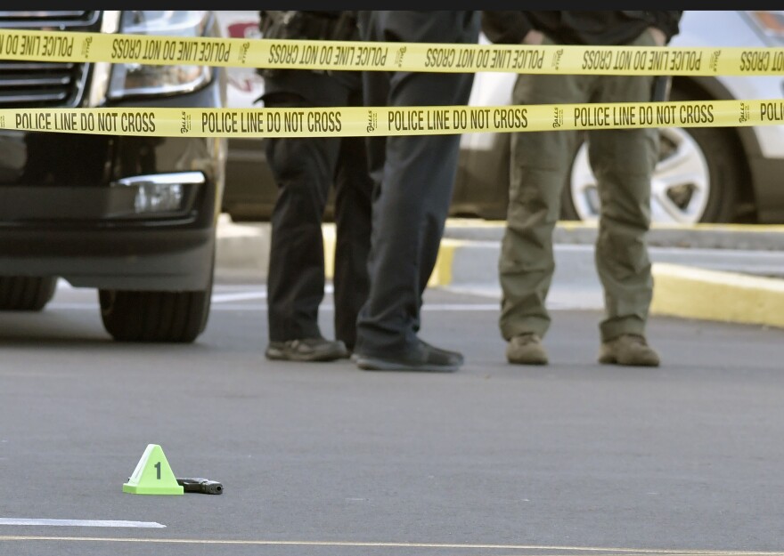 A gun lies on the ground inside a police barricade following the shooting at a Kroger that left two people dead and a suspect in custody, Wednesday, Oct. 24, 2018, in Jeffersontown, Ky.