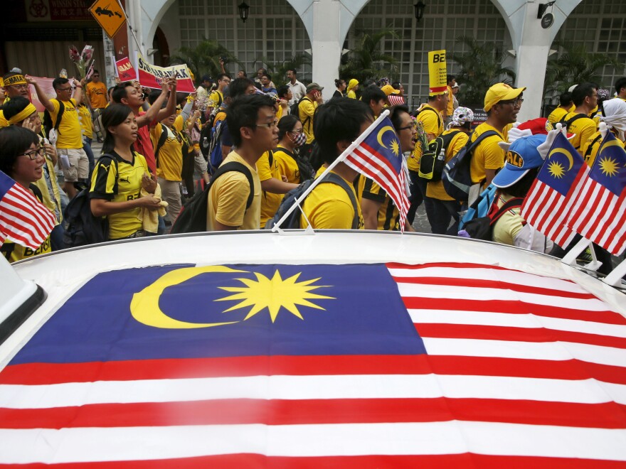 Supporters of pro-democracy group "Bersih" (Clean) pass a taxi decorated with Malaysian flags as they march toward Dataran Merdeka in Malaysia's capital city of Kuala Lumpur, on Saturday. The group is protesting alleged corruption at the top levels of government.