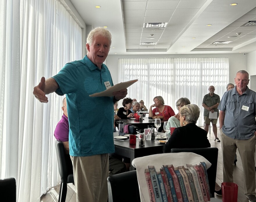 Man speaking to a group, with his arm out