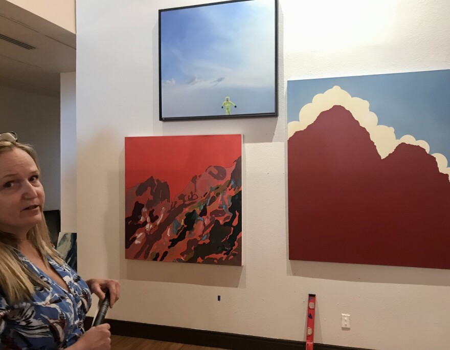 Curator Laurie Anne Farrell with three landscape pictures at the African American Museum