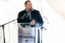 A man stands at a grey podium with the words "City of Springfield" on it. There's two microphones and a white background.