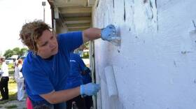 A volunteer paints over graffiti to kick off a graffiti abatement program Wednesday.
