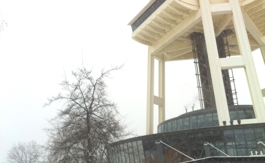 Constructi?on workers watching snow roll off top of Space Needle.