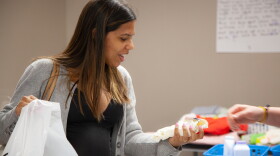 Talita Sonsini, from Brazil, picks bibs for her daughter at a community baby shower in Nashua, April 12, 2023.