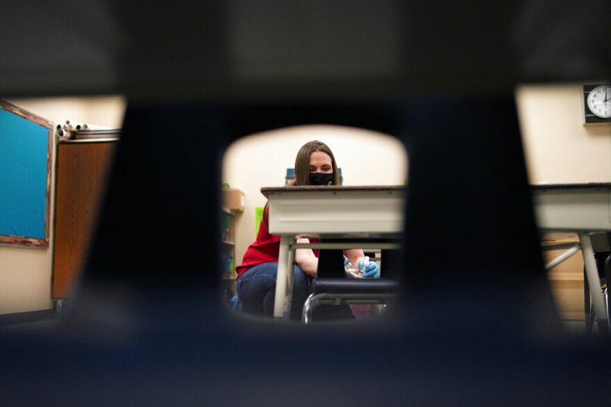 Amanda Pease cleans a classroom desk at Eisenberg Elementary School earlier this year as the Clark County School District reintroduced in-person learning.