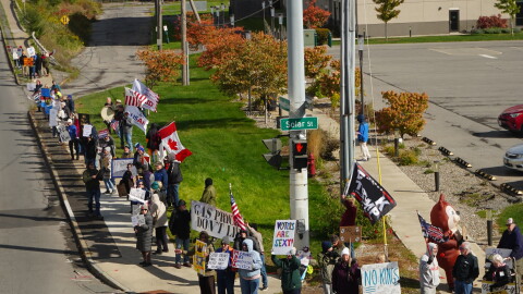 Ralliers stand at the street corner of Hiawatha Blvd. and Solar Street in Syracuse holding signs urging passersby to vote early.
